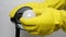 Human hand in yellow rubber glove unscrews damaged light bulb.