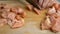 Human hands cutting on cubic, raw tender chicken breast or fillet with sharp kitchen knife into strips on wooden cutting