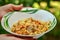 Human hands hold a bowl with pilau on a blurred background of gr