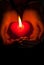 Human hands hold heart shaped burning candle