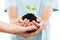 Human hands holding green sprout leaf growth at dirt soil