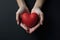 Human Hands Holding Heart Against Dark Background