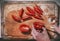 Human hands with knife cuts into slices red tomatoes on the old and dirty kitchen cutting board, ready to salad, top view