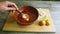 Human hands mix traditional borscht and sour cream with wooden spoon