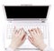 Human hands over laptop keypad during typing.