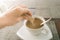 Human hands pouring sugar to cup of  hot coffee, focus on packet of sugar