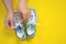 Human hands tie shoelaces on stylish white sneakers decorated on yellow background, top view, copy space for lettering. Studio