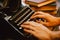 Human hands typing on vintage type writer machine and piles of books on wooden table - very selective focus.