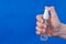 Human hands use spray, disinfectant, antiseptic in bubble, jar on blue background