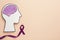 Human head cutout with brain near purple ribbon on beige, flat lay. Epilepsy awareness