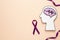 Human head cutout with brain near purple ribbons on beige, flat lay. Epilepsy awareness
