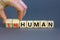 Human or inhuman symbol. Businessman turns wooden cubes and changes the word inhuman to human. Beautiful grey table grey