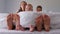 Human legs stick out from under the warm blanket. Feet of mom with children in the bedroom close-up.