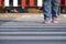 Human legs walking across the street on zebra crossing in public area