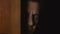 Human male face looks from a door from the darkness