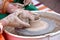 A human Potter works on a Potter`s wheel, making a ceramic pot from clay in a pottery workshop