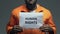 Human rights phrase on cardboard in hands of African-American prisoner, assault