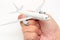 Human`s hand holding miniature passenger airplane on white background.