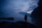 Human silhouette in a blue haze on the background of mountains and river. Thick fog in the evening twilight. Mysterious atmosphere