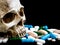 Human skull on multicolored of drug and capsule is on the black background. Close up. We are against drugs anti drugs, cure in c