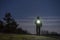 Human standing outdoor at night with flashlight and hoodie on head