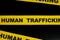 Human trafficking caution and warning concept. Yellow barricade tape with word in dark black background.