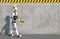 A humanoid robot builder in a construction helmet and a drill in his hand steps along a concrete wall.  Future concept with