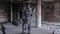 Humanoid robot stands with his back in hat in abandoned building. Footage. Android on date with glasses and bottle of