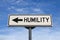 Humility white road sign with arrow, arrow on blue sky background