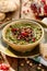 Hummus. Herb hummus with the addition of pomegranate seeds, parsley, olive oil and aromatic spices in a ceramic pot on a wooden