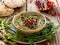 Hummus. Herbal hummus with the addition of pomegranate seeds, parsley, olive oil and aromatic spices in a ceramic pot on a wooden