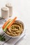 Hummus sauce in a bowl, sesame seeds, olive oil, cucumber and carrots on a light background