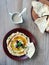 Hummus topped with olives and olive oil served with pita bread on plate over wooden table, vertical, flat lay