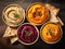 Hummus. Various hummus dips, red, yellow, white humus. Chickpea, pumpkin, carrot and beetroot hummus in bowls with pita bread on