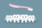 Humorous concept brushing teeth. Cute cartoon style teeth wash holding hands as a special forces by pink toothbrush on a blue back