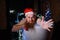 Humorous image of an evil santa claus taking a bath with christmas lights. A man with a red beard in a Santa Claus hat