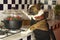 Humorous photography , dogs acting like humans . Boston Terrier in a black apron cooking vegetables in a steamer