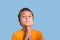 Humorous portrait of a boy begging for a request on a blue background in the studio