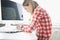 Hunched woman typing on computer keyboard at table