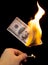 A hundred dollars burn in a fire on a black background