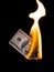 A hundred dollars burn in a fire on a black background