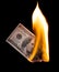 A hundred dollars burn in a fire on a black background