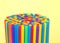 Hundreds of colorful plastic straws upright on yellow background