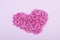 Hundreds of tiny pink heart-shaped hearts lie in the shape of a large heart as a symbol of romantic love