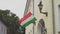 Hungarian flag on a flagpole waving on house.