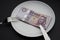 Hungarian forint Money on a white plate, next to a knife and fork. Breakfast, lunch and dinner service.