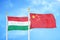 Hungary and China two flags on flagpoles and blue cloudy sky