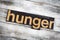 Hunger Letterpress Word on Wooden Background