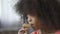 Hungry African American female kid eating cookie with appetite, close-up
