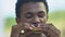 Hungry Afro-American teen boy eating delicious sandwich, lunch brake in school